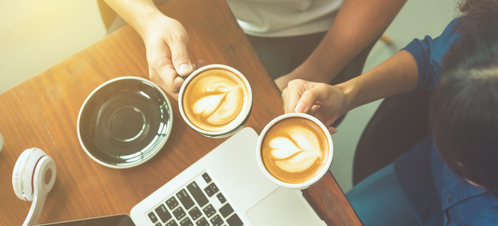 Koffie, notitieblok en laptop op een houten tafel tijdens een overleg