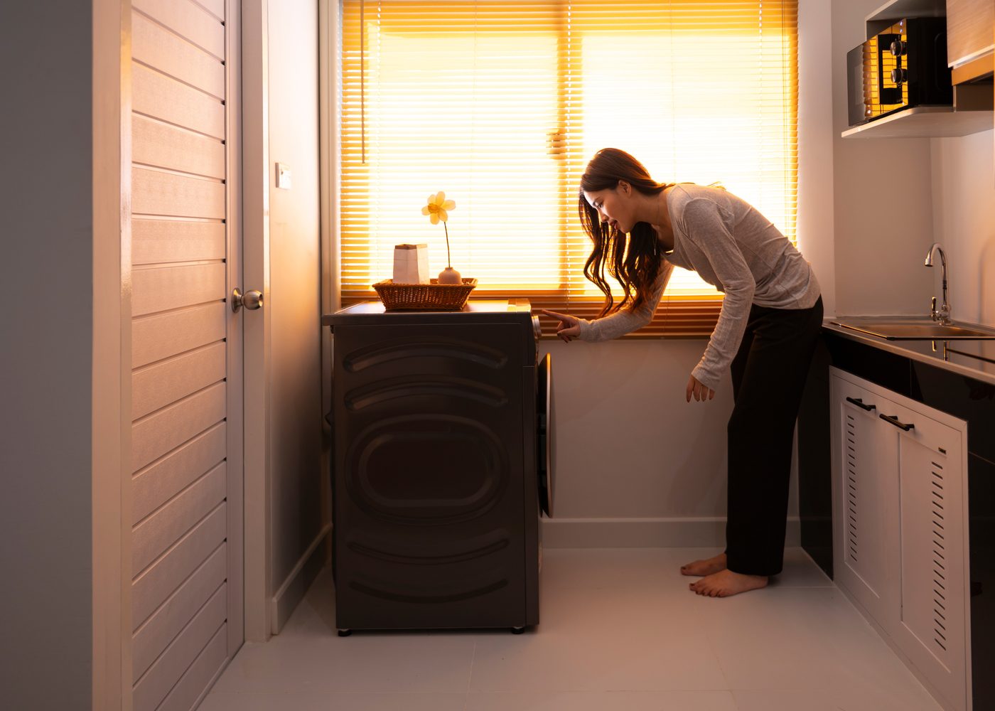 Begeleidster in de bijkeuken bij het raam, warm ochtendlicht door de jaloezie
